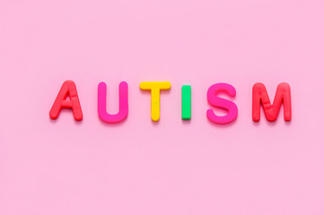 Word AUTISM on pink background, top view