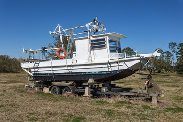 Vintage fishing boat stranded on land with trailer deep in the bayou