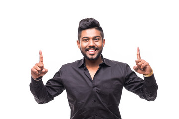 Portrait of excited bearded indian man in shirt pointing fingers up over white background