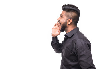 Portrait of Indian guy shouting loud, mouth open and hand cupped beside. Asian man standing on...