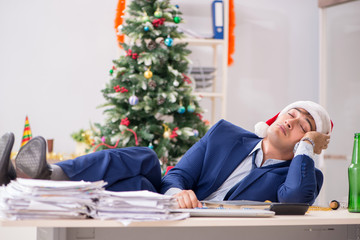 Young handsome employee celebrating Christmas at workplace 