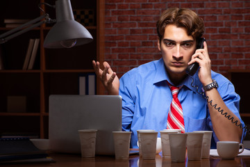 Young employee drinking coffee working at night shift 