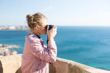 Stylish young woman outside the home makes photos of sea