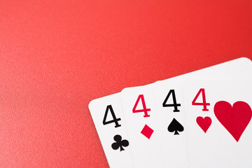 four four playing cards on a red background