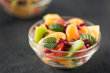 Bowl of healthy fresh fruit salad on black background.