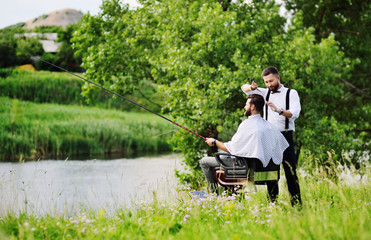 a professional hairdresser or Barber cuts the hair of a client in a Barber chair with a fishing rod...