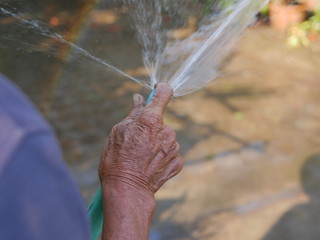 Close up of an old farmer / man's hand watering plants