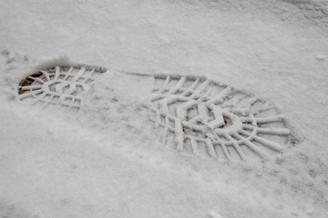 Traces of shoes on a snow-filled road. Imprint of a shoe in the snow.