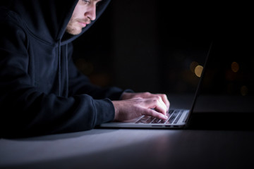hacker using laptop computer while working in dark office