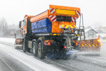 Snowplow truck removing dirty snow from city street or highway during heavy snowfalls. Traffic road...