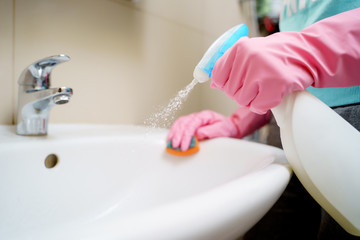 Photo of hands in pink rubber gloves washing sink in bath