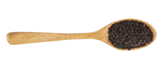 Black sesame seeds in a wooden spoon isolated on white background. Top view. Flat lay