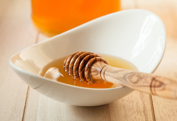 Honey dipper in a porcelain bowl with fresh honey
