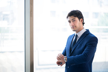 Fototapeta premium Young handsome businessman standing at the window 