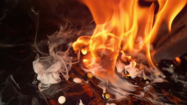 SLOW MOTION, MACRO, DOF: Big metal tongs slowly swirl a blade in hot oil during the heat treatment process. Blacksmith forging a blade smothers the raging flames on a blade by dipping it into water.