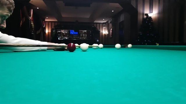 young handsome man puts a billiard ball in the pocket