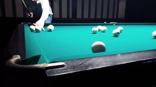 young handsome man puts a billiard ball in the pocket