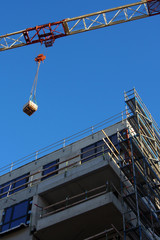 Wohnungsbau: Baukran &uuml;ber Baustelle mit Kranlast