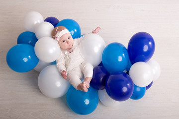 little girl child lies in a cloud made of balloons