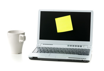 Empty yellow sticky paper note on laptop with cup of coffee with copy space over white