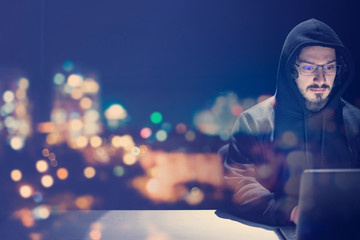hacker using laptop computer while working in dark office