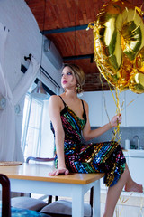 Young woman with golden balloons on her thirty years birthday. Indoor location. Person is in vintage 80th dress and hairstyle. At home