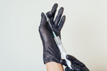 Of man hands with black gloves holding a syringe and vial of medicine. Preparation for injection, on a white background.