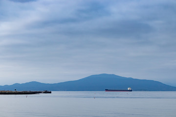 Cargo ship in the ocean with mountains on background
