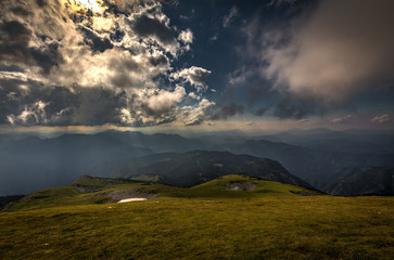 View from Rax plateau, full of fresh, green grassy meadow with blue dramatic cloudy sky to valley and alpine hills, Raxalpe, Schneeberg massif, Alps, Lower Austria