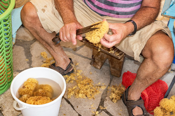 Sponge Cutter trims sea sponge tampon in street shop on Symi island (Rhodes, Greece)