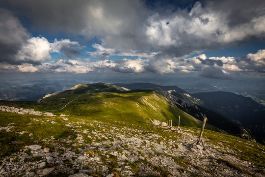 Rocky path and grassy rax plateau on hike Dambocksteig from Schneeberg, highest peak Kosterwappen, along Waxriegel to Puchberg in the cloudy sunset, Raxalpe, Lower Austria