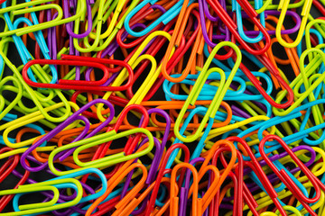 Pile of multi color paper clips on the black board