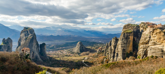 Four monasteries of Meteors: Roussanou, Monastery of Agios Nikolaos Anapafsas, Varlaam and Grand Meteora scattered on the steep cliffs with mountains panorama , Trikala, Thessaly, Greece