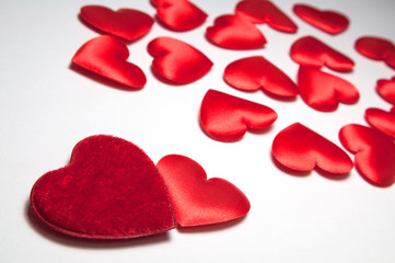 Two red hearts are near and many small blurred hearts. The concept of two loving people who have found each other among hundreds of other lonely hearts. Decorative hearts for Valentine's day.