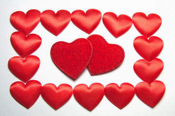 Background of two large velvet burgundy and many small silk red hearts in a frame. Decorative hearts for Valentine's day or Wedding.