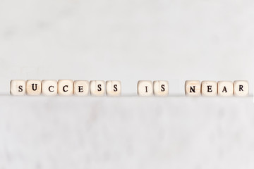 Cubes with the words SUCCESS IS NEAR on a gray concrete background. Selective focus.