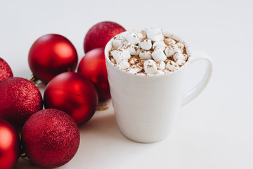 Cocoa mug with marshmallows on the background of red christmas balls