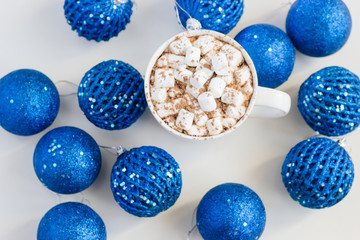 Cocoa mug with marshmallows on the background of blue christmas balls