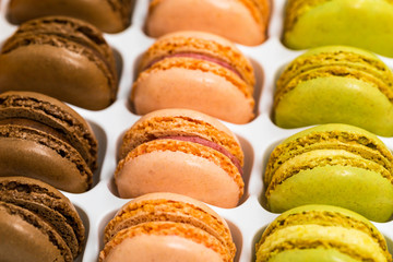 Colorful Macaroons Chocolate, Pistachio, Cherry, Orange, Vanilla Flavor Background. Selective focus.