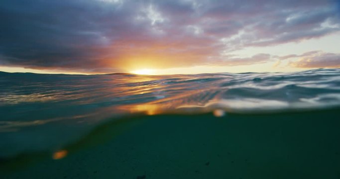 Beautiful golden sunset into the ocean, over under split view from in the water, abstract nature landscape