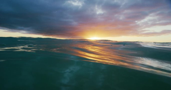 Beautiful golden sunset into the ocean, over under split view from in the water, abstract nature landscape