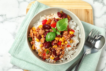 Tasty chili con carne served with rice on marble table, flat lay