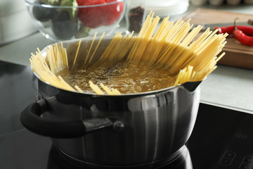Cooking spaghetti in pot on electric stove