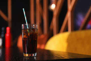 Glass of refreshing cola with ice on table indoors. Space for text