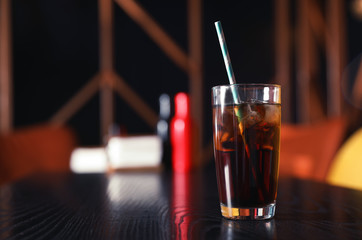 Glass of refreshing cola with ice on table indoors. Space for text