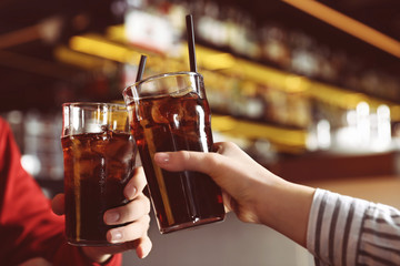 Young couple with glasses of refreshing cola indoors, closeup