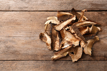 Delicious dried mushrooms on wooden background, top view with space for text