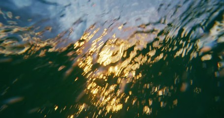 Beautiful golden sunset into the ocean, over under split view from in the water, abstract nature landscape