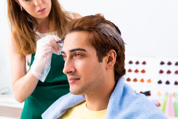 Woman hairdresser applying dye to man hair