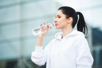 Fitness. Sport and healthy lifestyle concept - woman drinking water after exercising in park